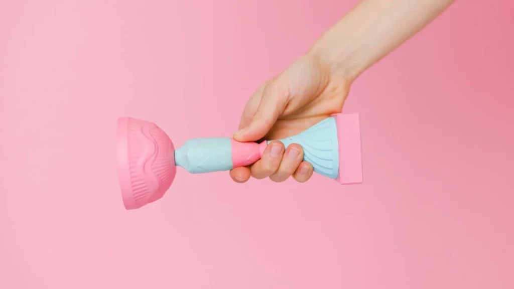 hand holding a pink and blue trophy on a pink background.