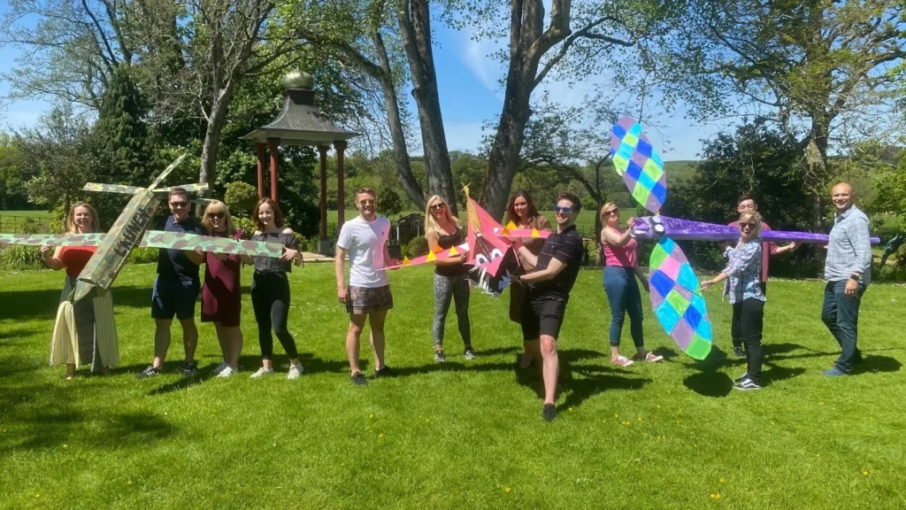 Launch Online Team Outside in the sun showing off handmade cardboard animals, smiling