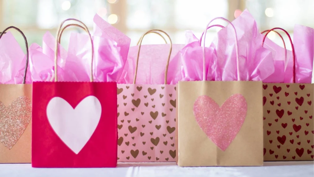 Heart decorated gift bags lined up with colourful tissue paper sticking out the top
