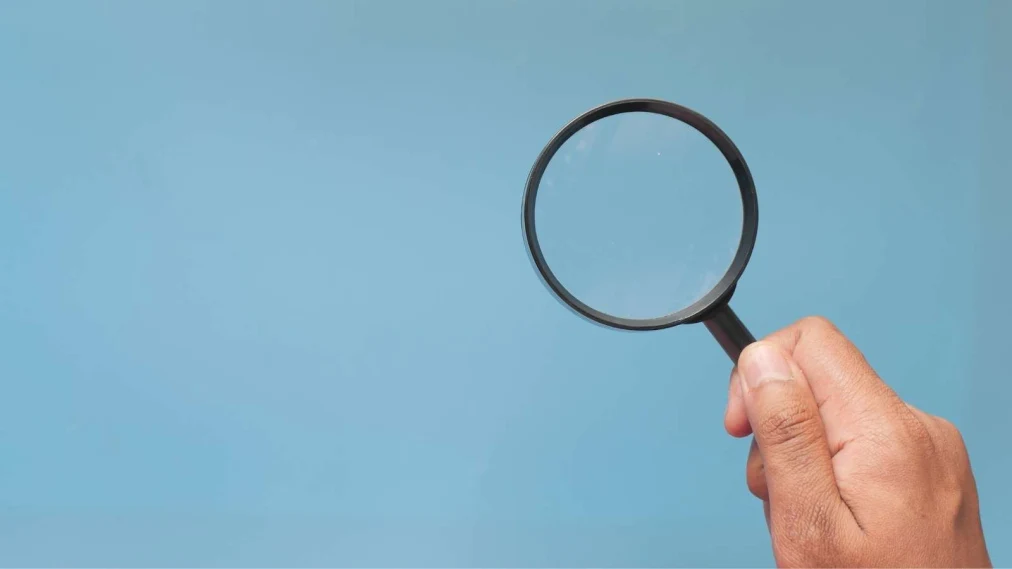 Hand holding magnifying glass on a blue background