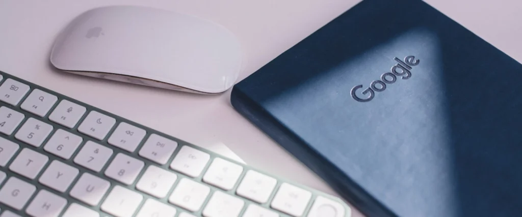 Apple mouse and keyboard next to a google notebook