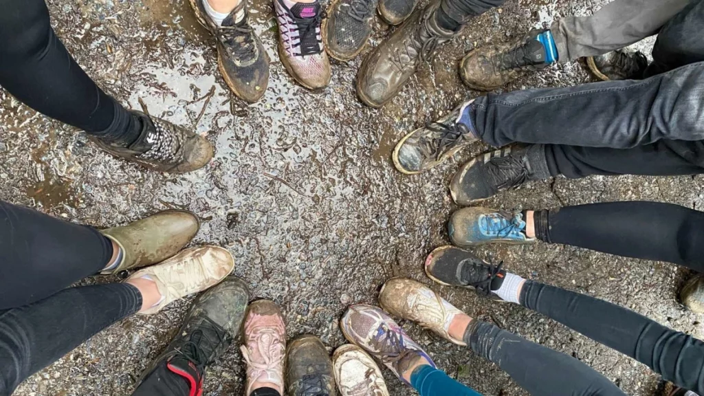 Image of people shoes arranged in a circle covered in mud
