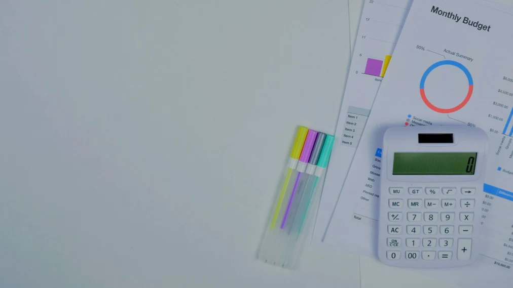 Banner image of monthly budget paper reports, a calculator and highlighter pens