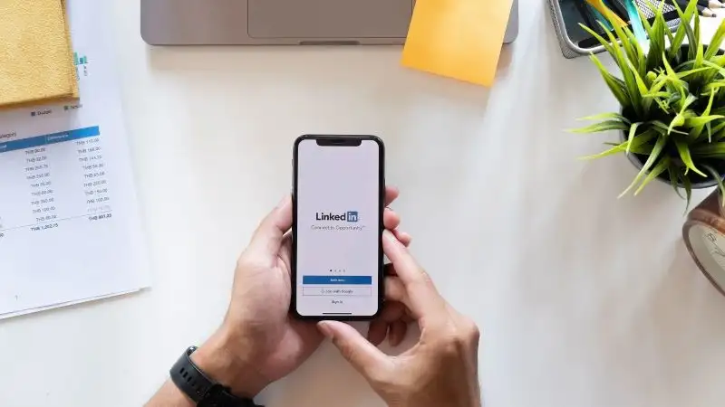 Above shot of hands holiding a mobile phone logging into LinkedIn