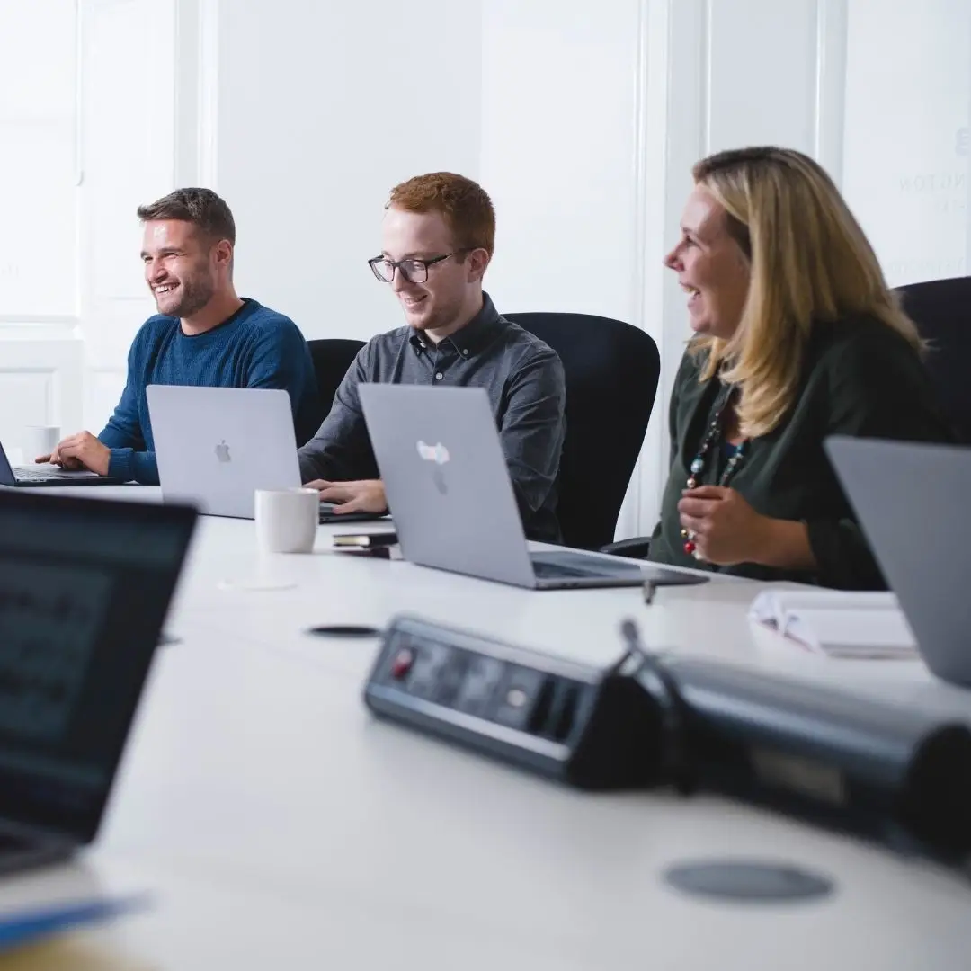 Launch team members sat at a desk with laptops smiling.