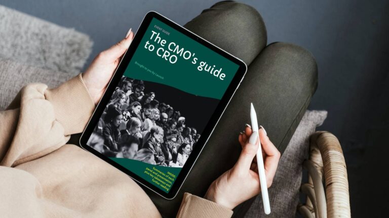 A landscape image of someone sitting looking at a tablet with the CMO's guide to CRO on screen