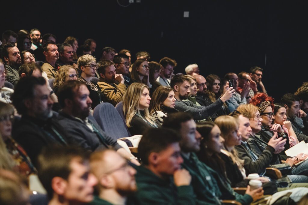 Audience seated in a dark theatre at the CMO Summit hosted by performance marketing agency Launch in March 2024