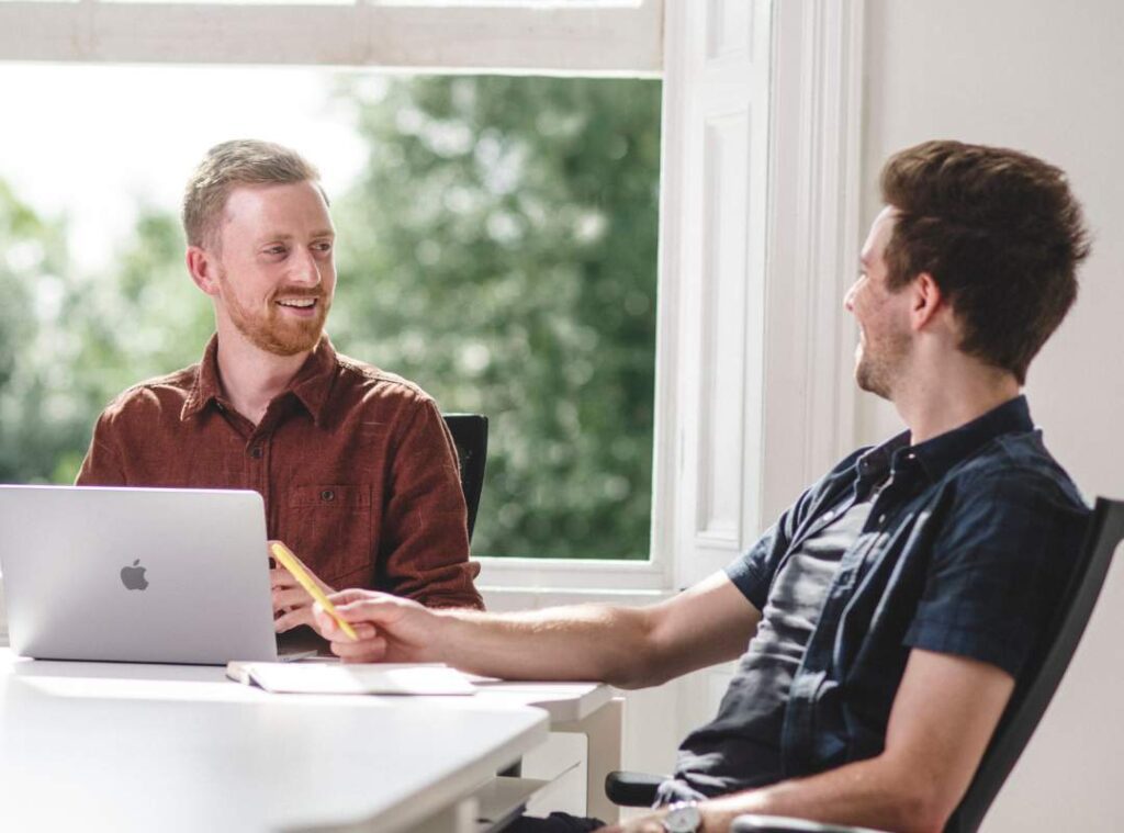 Elliot and Mike smile in a meeting