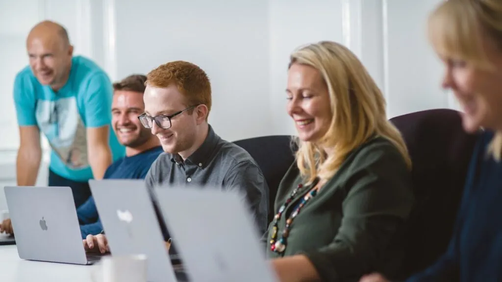 The Launch team in a meeting with laptops, smiling.